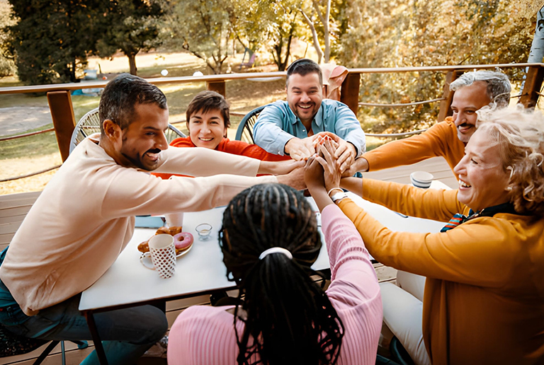 Group of people joining hands during a Sahara Oasis community activity.