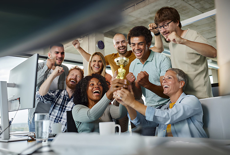 Diverse team celebrating success and holding a trophy together in a modern office.