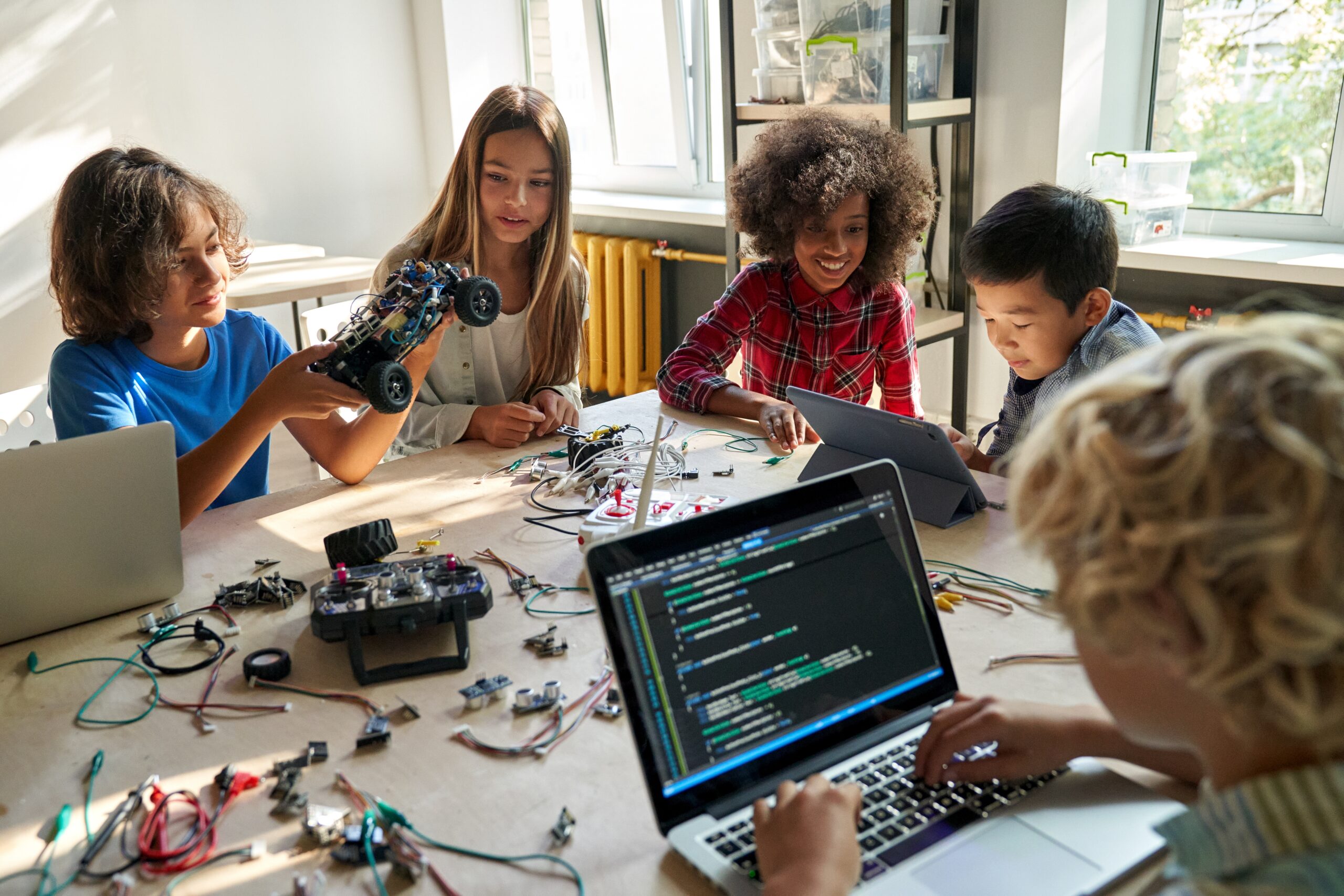 Group of students coding and testing a robotic car in a classroom